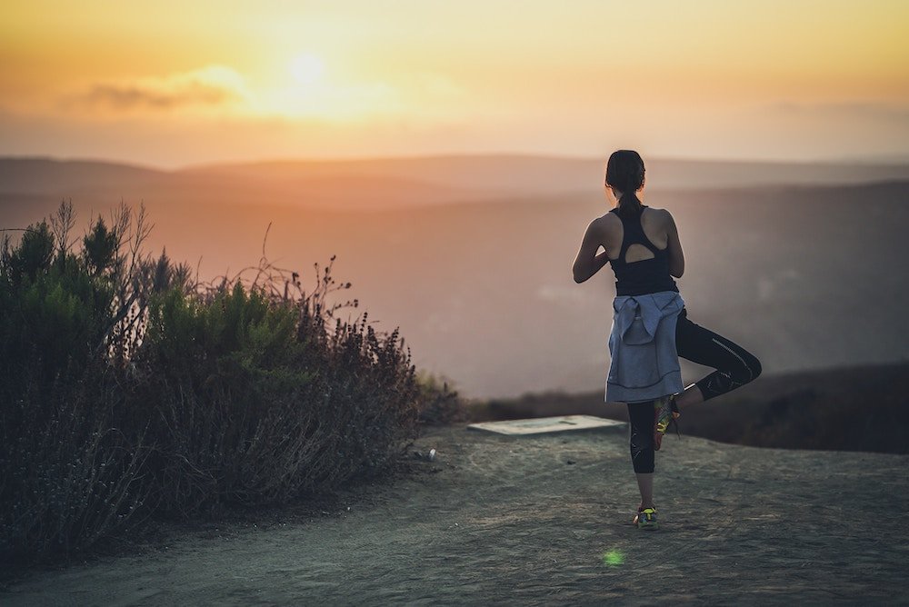 Person exercising and doing yoga at sunset